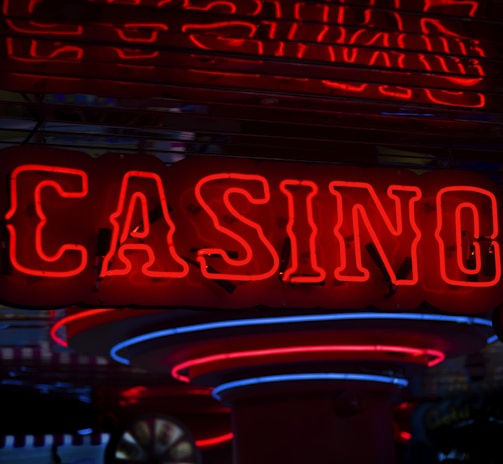 Neon lights display the word 'CASINO' in bright red, standing out against a dark background. The vibrant glow reflects a lively and bustling atmosphere.